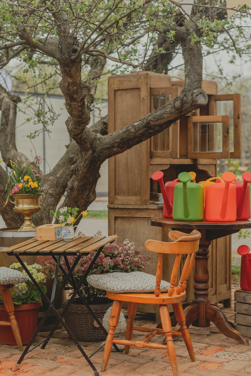 Giardino di un caffè con mobili in legno e annaffiatoi colorati.