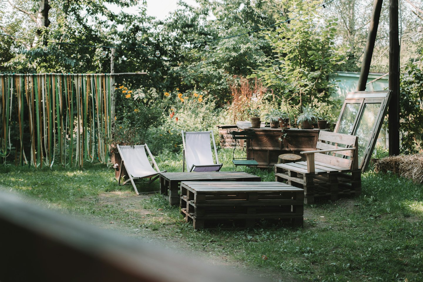 Mobili in pallet di legno riciclato in un'area salotto in giardino.