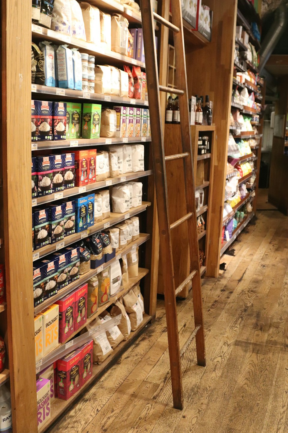 Scaffali di legno di un negozio di alimentari pieni di vari prodotti alimentari confezionati.